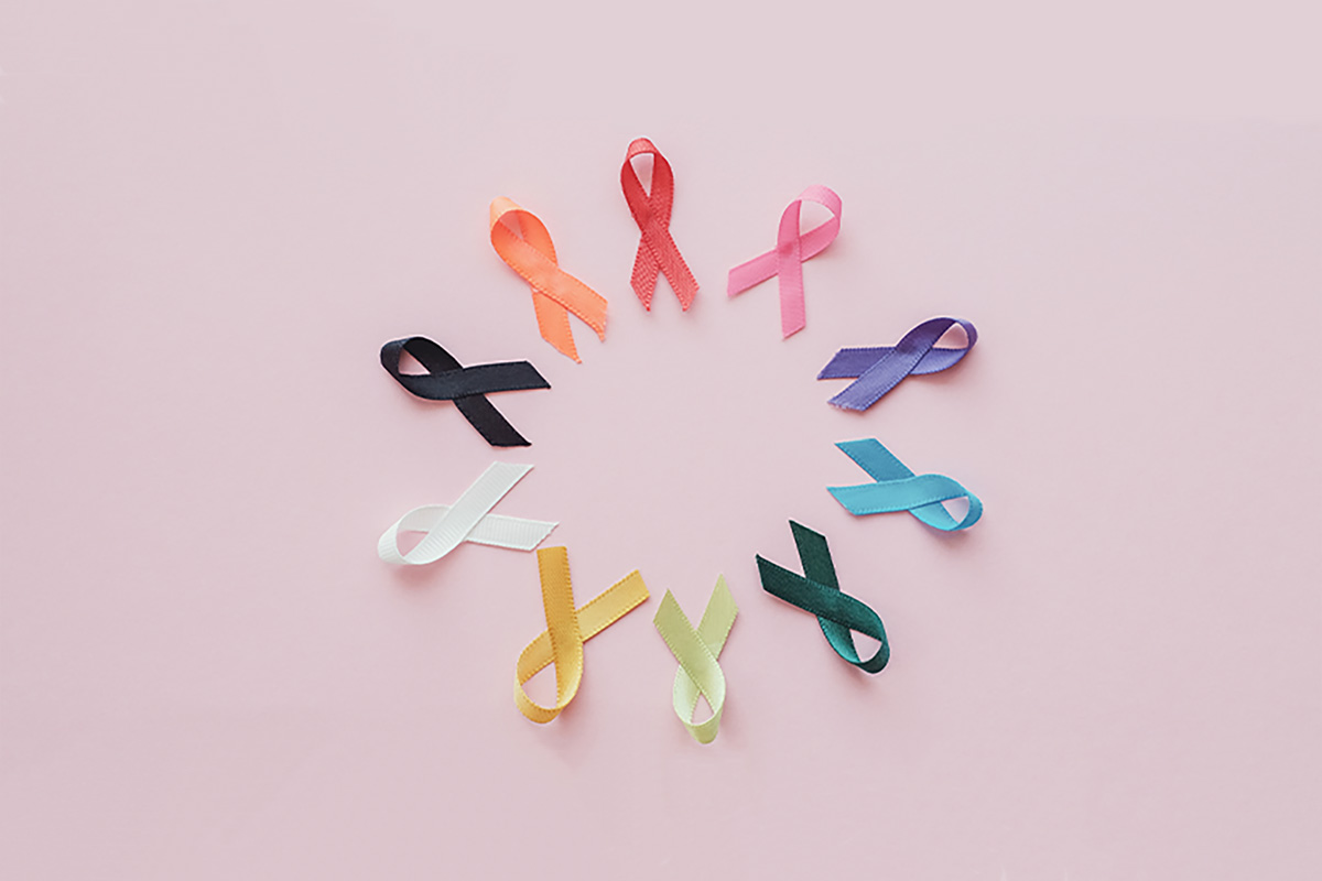 Cancer awareness ribbons placed on a pink background.