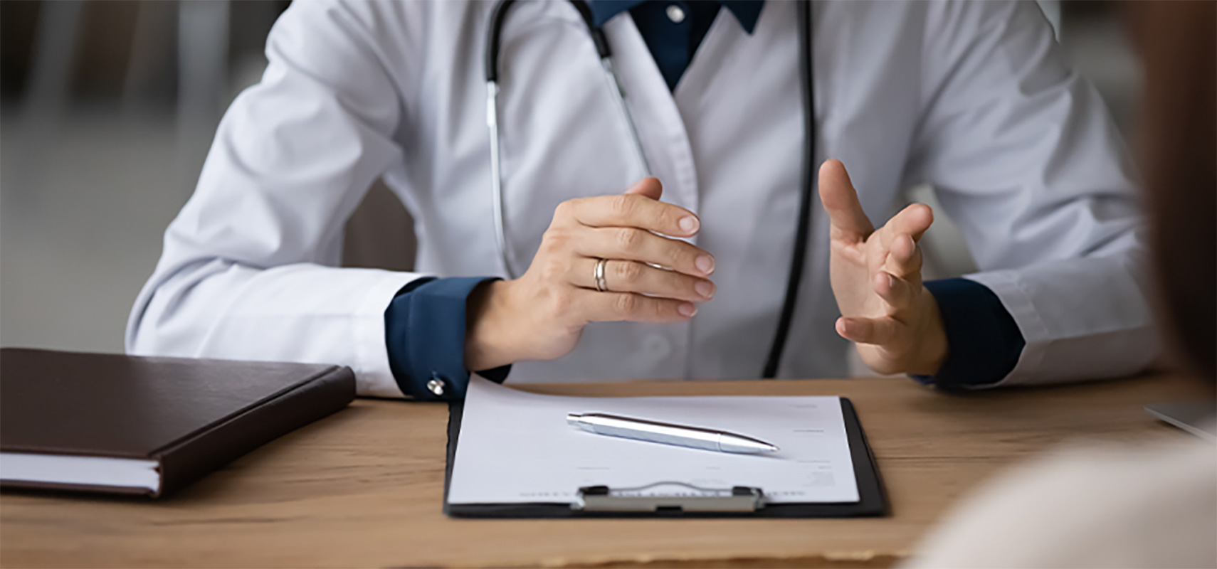A doctor with a clipboard speaking with a patient.