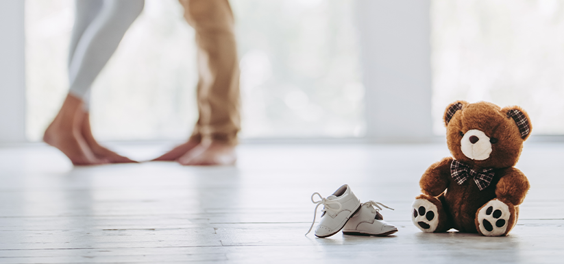 Expecting couple with teddy bear and baby shoes ready.