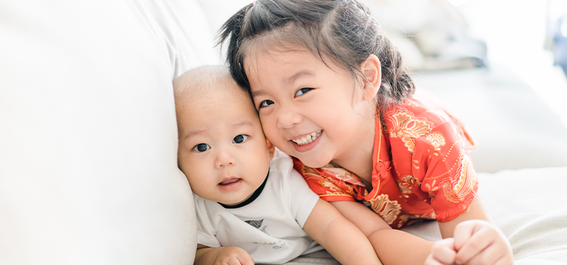 Little sister hugging her baby brother.