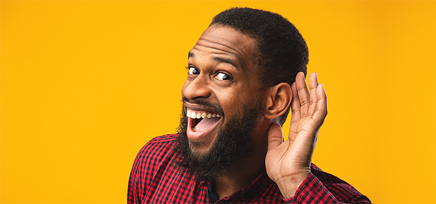 A man with his hand behind his ear, listening.