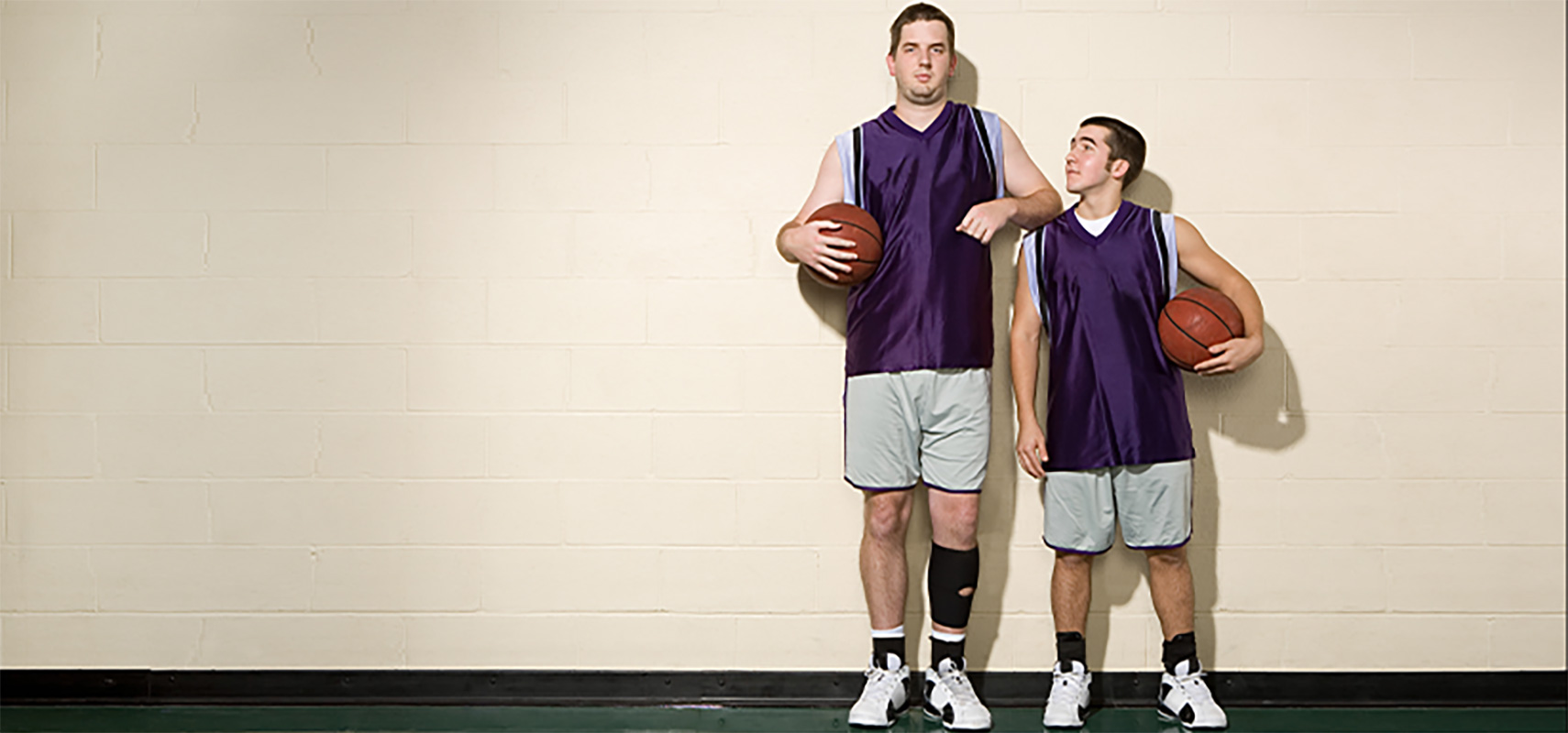 Tall and short basketball players standing side-by-side.